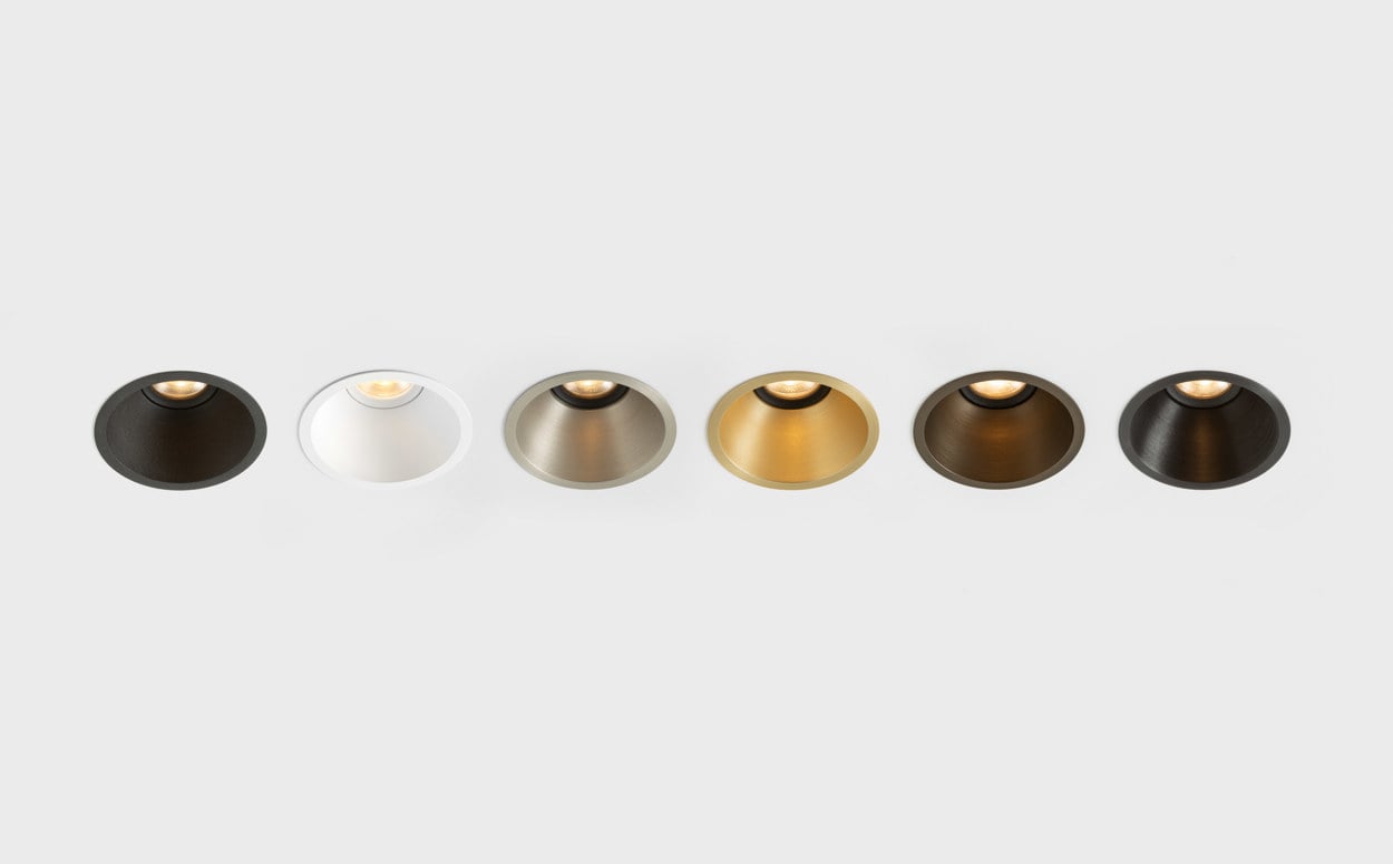 A row of Klevr recessed spotlights displayed in a selection of finishes, highlighting the product’s refined circular form and material versatility. From dark and warm metallic tones to brushed aluminium and white, each finish enhances Klevr’s minimalist design while allowing seamless integration into a wide range of architectural interiors.