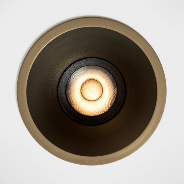 Front-facing close-up of Klevr recessed spotlight in Bronze finish. The minimalist circular form sits perfectly flush with the ceiling, while the deeply recessed light source creates a soft, glare-free glow. Precision optics and a refined metallic interior combine to deliver visual comfort and architectural elegance.