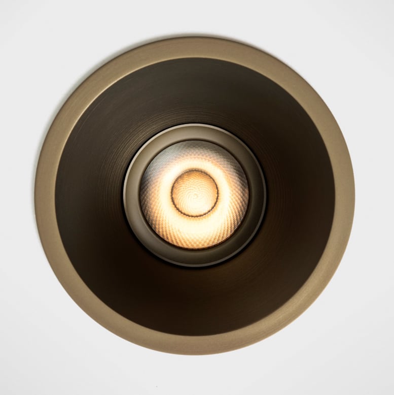 Front-facing close-up of Klevr recessed spotlight in Bronze finish. The minimalist circular form sits perfectly flush with the ceiling, while the deeply recessed light source creates a soft, glare-free glow. Precision optics and a refined metallic interior combine to deliver visual comfort and architectural elegance.