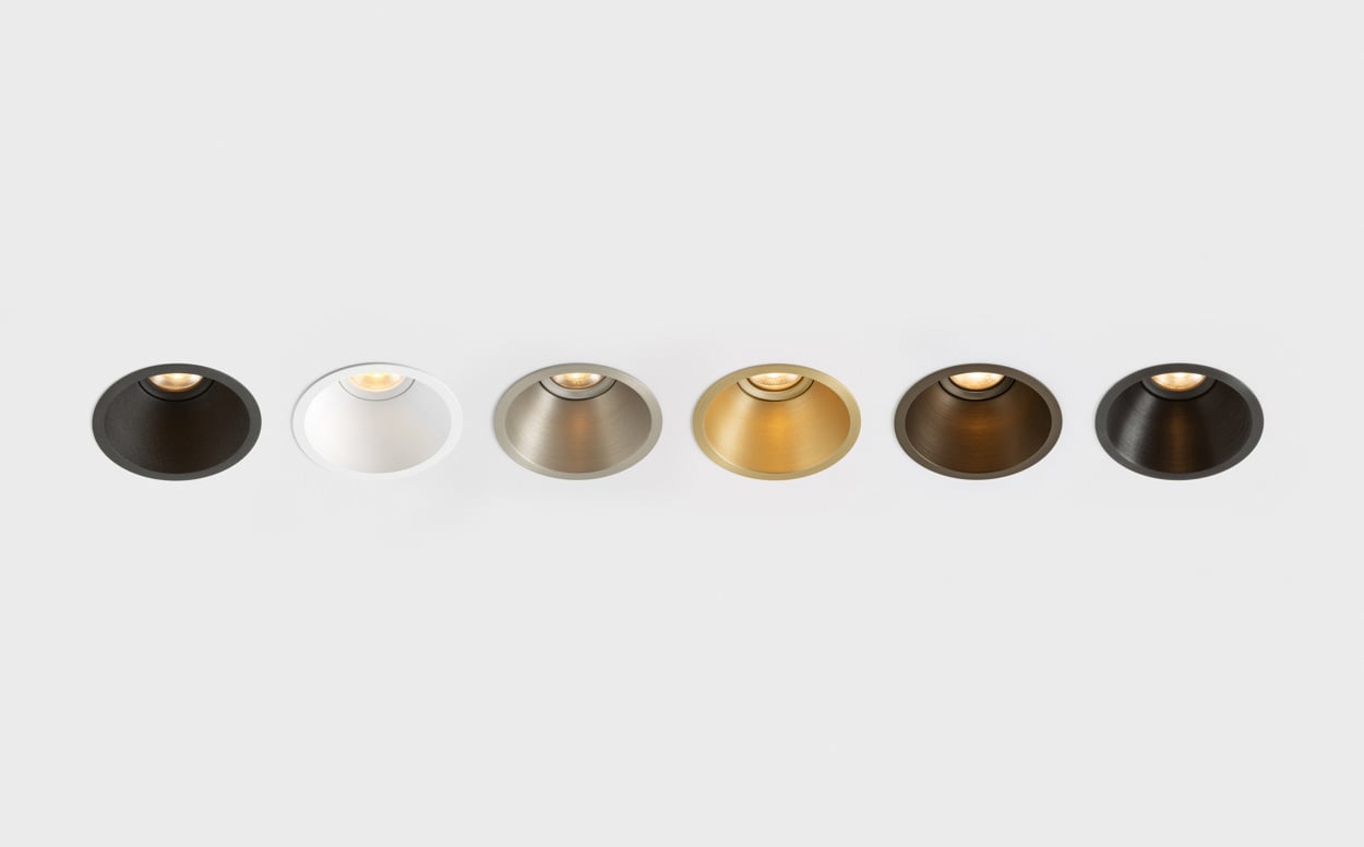 A row of Klevr recessed spotlights displayed in a selection of finishes, highlighting the product’s refined circular form and material versatility. From dark and warm metallic tones to brushed aluminium and white, each finish enhances Klevr’s minimalist design while allowing seamless integration into a wide range of architectural interiors.